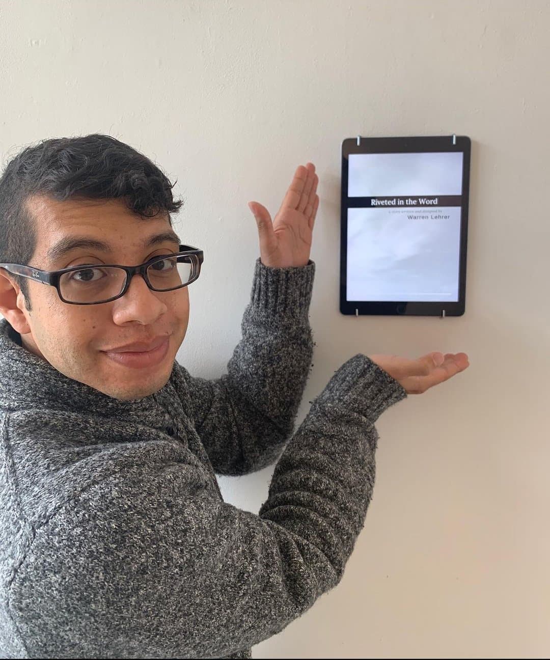 Artemio gesturing toward a tablet mounted on a wall